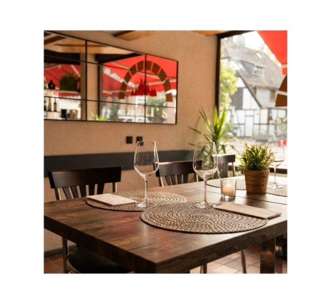 Gemütlicher Gastraum mit Holztischen und Blick nach draußen bei Eroli's Pizzeria
